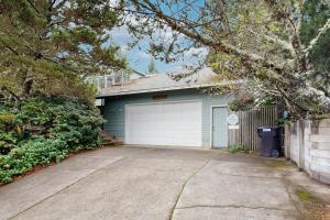 a green house with a garage with a driveway at Cliffside Serenity in Oceanside