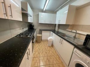 eine Küche mit weißen Schränken und schwarzen Arbeitsplatten in der Unterkunft Park House Goodmayes, Ilford London in Goodmayes