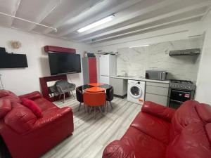 ein Wohnzimmer mit einem roten Sofa und einer Küche in der Unterkunft Park House Goodmayes, Ilford London in Goodmayes