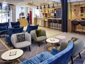 a lobby with blue chairs and tables and a bar at Mercure Paris la Défense Grande Arche in Nanterre