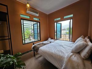 a bedroom with a bed and two windows at Stay HostelandBar in Làng Cac