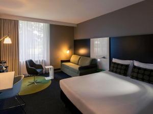 a hotel room with a large bed and a couch at Mercure Hotel Zwolle in Zwolle +82 photos