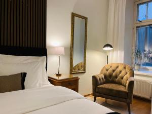 una camera da letto con un letto, una sedia e uno specchio di Luotsi 1911 Suite a Helsinki