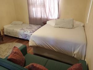 a bedroom with two beds and a couch and a window at 63 On Main in Zuurbraak