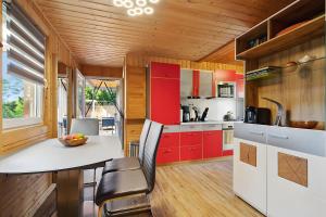 een keuken met rode kasten en een witte tafel en stoelen bij Ferienhaus 249 - Haus Seeblick in Kleinwolschendorf