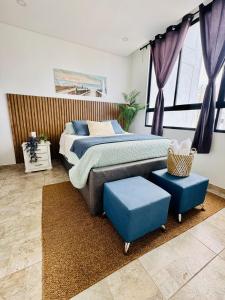 um quarto com uma cama e dois pufes azuis em Rodadero Cmol945 em Santa Marta