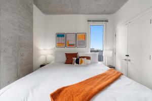 a white bedroom with a large white bed with orange blanket at Spacious 3BR Urban Getaway w Gym in Chicago