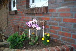 a garden with flowers in front of a brick wall at Ferienhaus Landskron in Wangerland