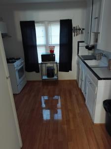 a kitchen with white cabinets and a wooden floor at Zen Gem Near Downtown Detroit and Grosse Pointe in Detroit