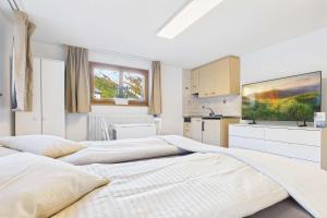 two beds in a white room with a kitchen at Comfortable studio near Saas-Fee ideal for couples in Saas-Grund