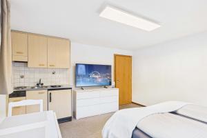 a bedroom with a bed and a kitchen with a tv at Comfortable studio near Saas-Fee ideal for couples in Saas-Grund