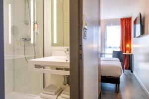 a bathroom with a sink and a shower and a bed at Mercure Paris Malakoff Parc des Expositions in Malakoff +48 photos