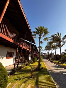 um edifício com palmeiras junto a um passeio em Pousada Encantos do Coqueiro em Luis Correia