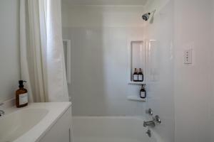 Un baño blanco con bañera y ducha con botellas de vino. en Short North Convention Private Parking Pets, en Columbus