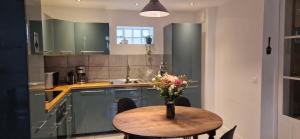 a kitchen with a wooden table with a vase of flowers on it at Bleautiful "Aliénor" Charmant appartement avec terrasse in Fontainebleau