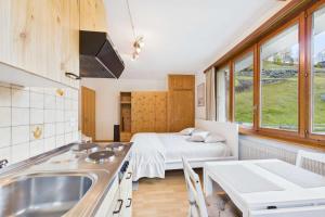 a kitchen with a sink and a bed in a room at Comfortable studio with balcony and panoramic view in Saas-Grund