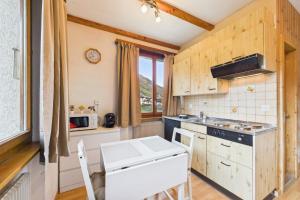 a kitchen with wooden cabinets and a stove top oven at Comfortable studio with balcony and panoramic view in Saas-Grund