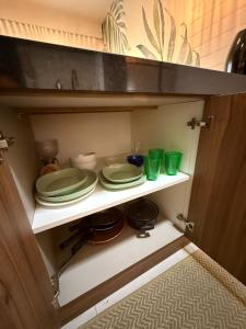 einem Schrank mit Tellern und Tassen auf einem Regal in der Unterkunft Flat na Av JK in Sao Jose do Rio Preto