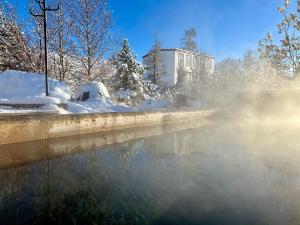 um corpo d'água com neve e um prédio ao fundo. em Guesthouse Storu-Laugar em Laugar