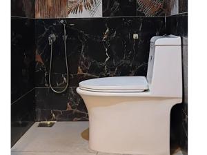 a white toilet in a bathroom with a black wall at La Goodwill Garden Luxury villa in Auroville +37 photos