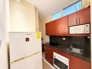 Una cocina con refrigerador blanco y gabinetes de madera. en Suite en Machala, en Machala