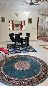 a dining room with a table and chairs and a rug at Wan Z Homestay Pasir Mas in Pasir Mas
