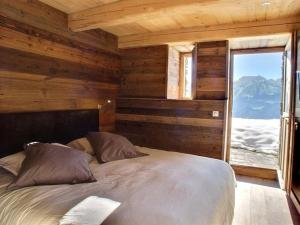 een slaapkamer met een groot bed met een raam bij Les Alpages du Soleil in La Rosière