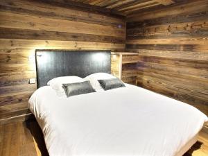 een slaapkamer met een wit bed en houten wanden bij Les Alpages du Soleil in La Rosière +42 foto's