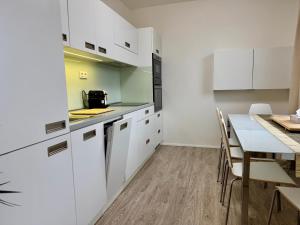 a kitchen with white cabinets and a table with chairs at Family Apartment 104 in Špindlerův Mlýn