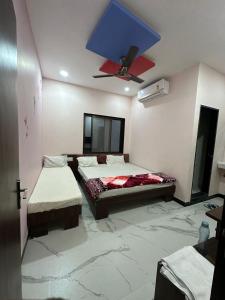 a bedroom with two beds and a ceiling fan at Hotel Krishna Raj in Ujjain