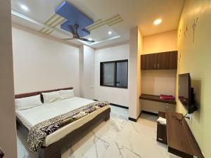 a bedroom with a bed and a flat screen tv at Hotel Krishna Raj in Ujjain
