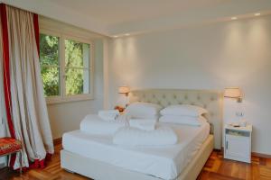 a white bedroom with a large white bed with white pillows at Villa Aria in San Felice del Benaco +62 photos