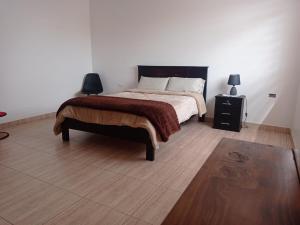 a bedroom with a bed and a wooden floor at Casa en Atuntaqui in Atuntaqui