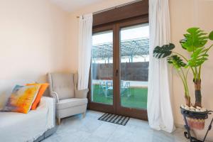 ボルムホスにあるLuxSevilla Bormujos Piscina Free Parkingのリビングルーム(椅子付)、ガラスのスライドドア