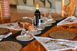 a wooden table with plates and glasses and a bottle of wine at Eco Mara Tented Camp in Ololaimutiek