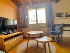 迈松拉菲特Joli duplex refait à neuf, face gare, près Ermitage的客厅配有电视、桌子和两把椅子