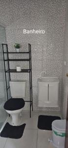 a bathroom with a toilet and a sink and a shelf at Aconchego Brasileirinho Para-ti in Paraty