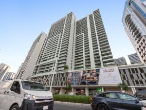 zwei Autos parkten vor einem großen Gebäude in der Unterkunft Reva Residence Comfort Suite - 1Bedroom with Sofa Bed in Dubai