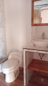 a white bathroom with a toilet and a sink at Casa de david in Máncora