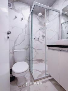 Un baño con inodoro y ducha de cristal. en Lumiére, en Poços de Caldas