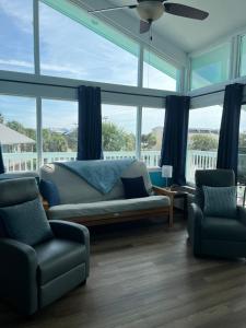 a living room with a couch and chairs and windows at Sky Blue 321 in Cedar Key