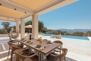 a dining room with a table and chairs and a pool at Euphoria Hill Villa, By TK Property Management in Kalamaki