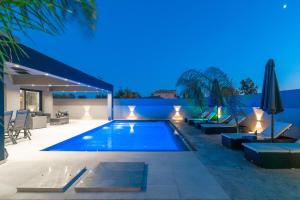 a swimming pool in the backyard of a house at night at Hollywood Exclusive Villa, by TK Property Management in Laganas +44 photos