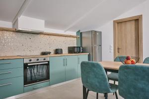 a kitchen with blue cabinets and a table and chairs at Sofita Sea View Apartment, By TK Property Management in Argasi