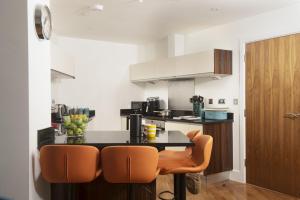 a kitchen with a black counter and orange chairs at 10 The Whitehouse, Watergate Bay in Mawgan Porth