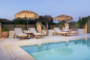 a group of chairs and umbrellas next to a swimming pool at Porta Verde Luxury Residence, By TK Premium Stays in Laganas
