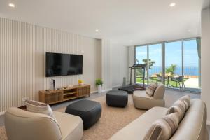 een woonkamer met een bank, stoelen en een televisie bij OurMadeira - GrandView Cristo Rei in Garajau