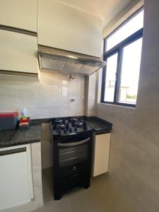 a kitchen with a black stove and a window at Thainá · Apartamento amplo proximo a praia do Bessa. in Nossa Senhora do Livramento