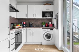 OlpenitzdorfにあるFerienwohnung Balance Hus Olpenitzのキッチン(白いキャビネット、洗濯機、乾燥機付)