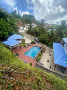 an overhead view of a swimming pool with blue umbrellas at Villa Mamalouken App Maloe in Rivière-Pilote